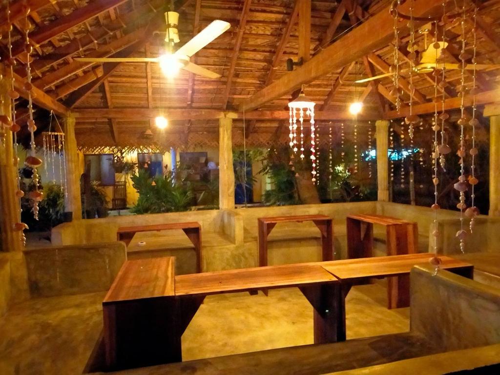 a restaurant with a wooden table and chairs at Eastwind Surf Camp in Arugam Bay