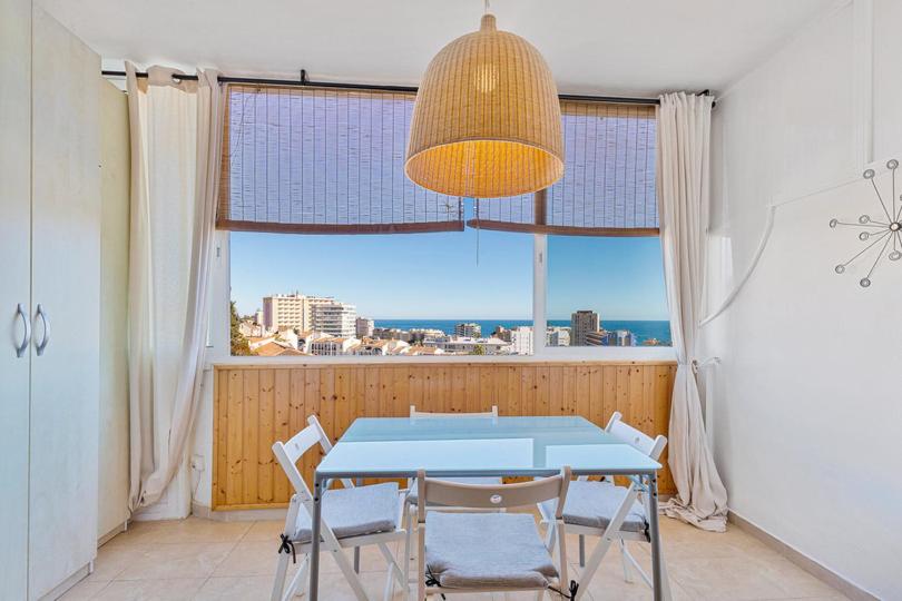 une salle à manger avec une table, des chaises et une grande fenêtre dans l'établissement Cozy Fuengirola apartment with sea view & pool, à Fuengirola