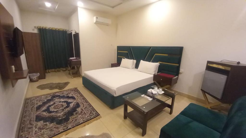 a bedroom with a bed and a couch and a tv at Royalton Inn Hotel in Lahore