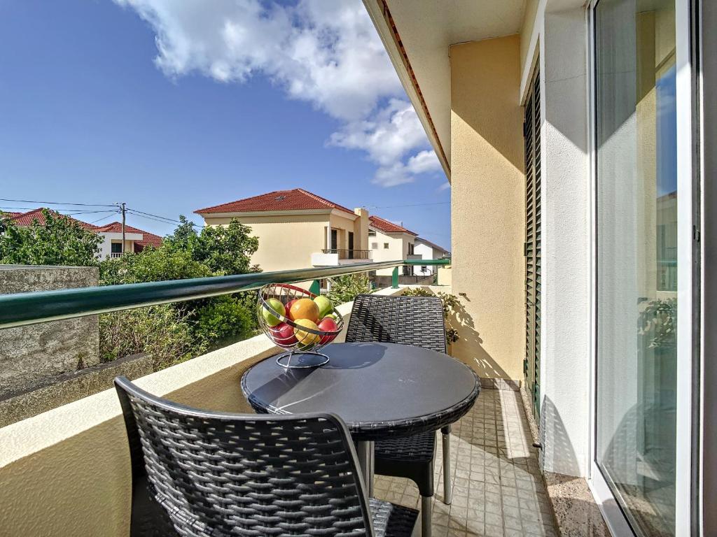 a table and chairs on a balcony with a bowl of fruit at Atlantic Breeze by Atlantic Holiday in Porto Moniz