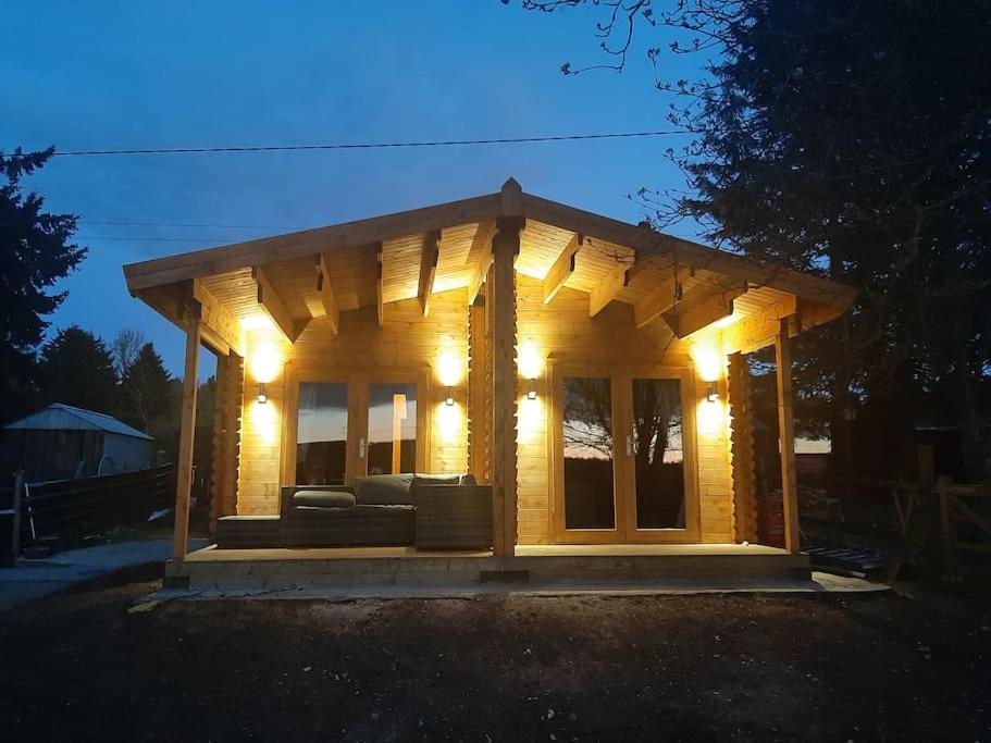 a small wooden house with lights on it at Bishy Barnabees country lodge with hot tub in Swaffham