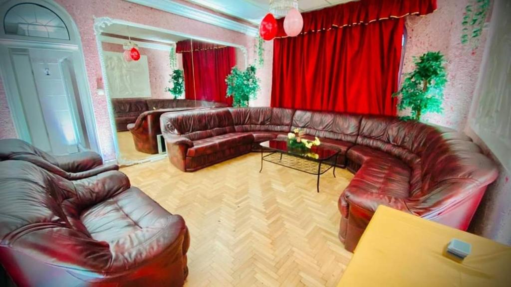 a living room with leather furniture and red curtains at Private Party Villa in Budapest