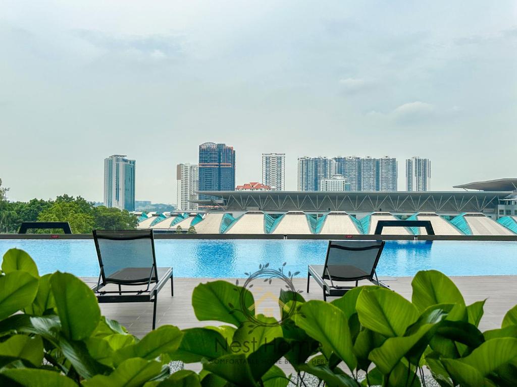two chairs in front of a swimming pool with a city at Twin Tower Residence by Nest Home【5 mins walk to CIQ】 in Johor Bahru