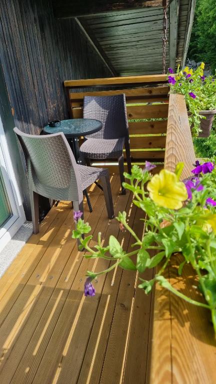 two chairs and a table on a deck with flowers at Apartments Domačija Mlaker in Podčetrtek