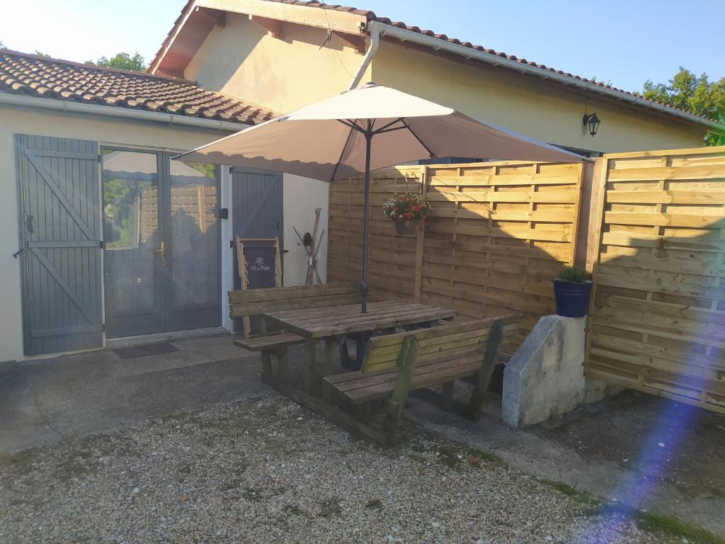 Vensac的住宿－L'abri côtier，房屋前带雨伞的木凳