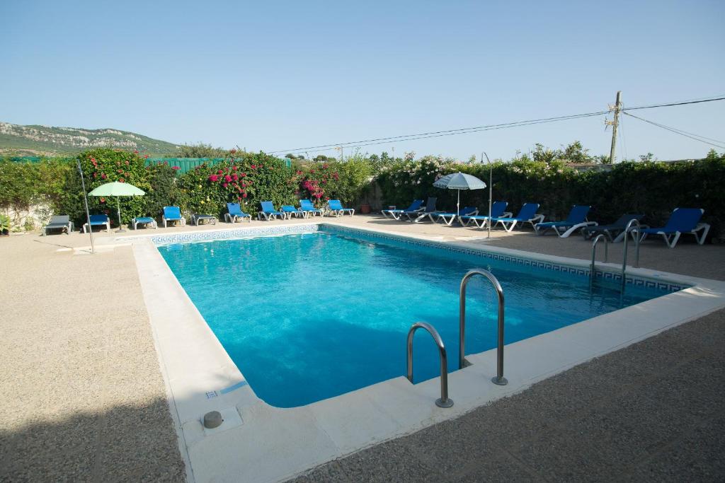 a large swimming pool with blue chairs and umbrellas at Apartamentos Bolonia Paraiso in Bolonia