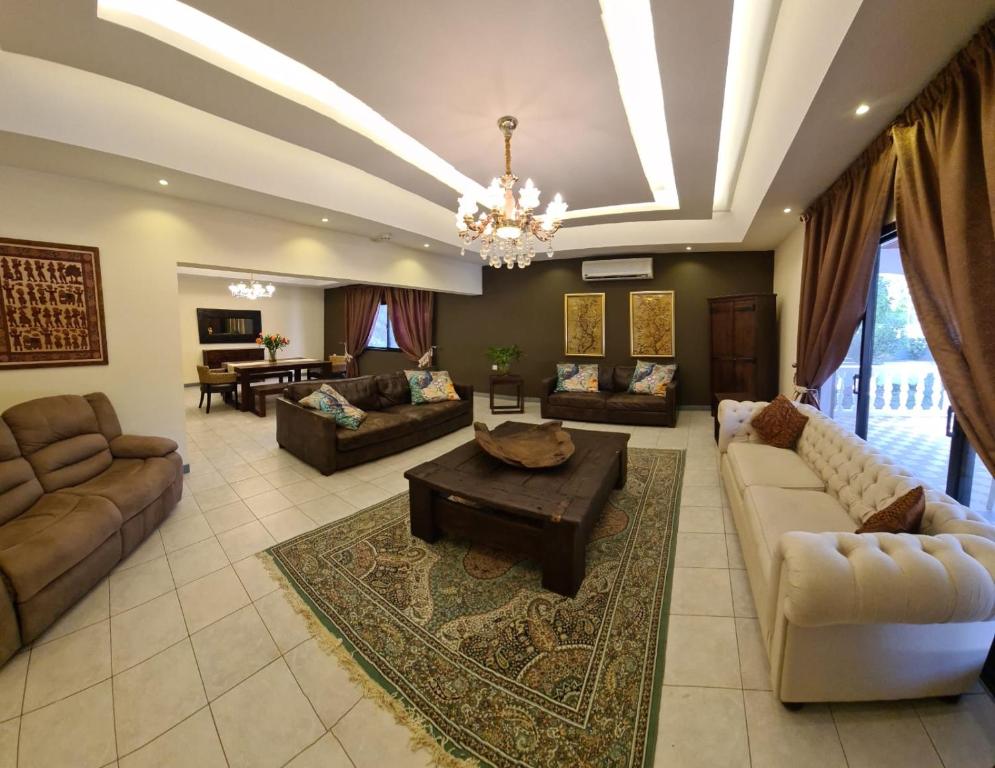 una gran sala de estar con sofás y una lámpara de araña. en Luxury holiday villas in Bahrain for Families en Bārbār