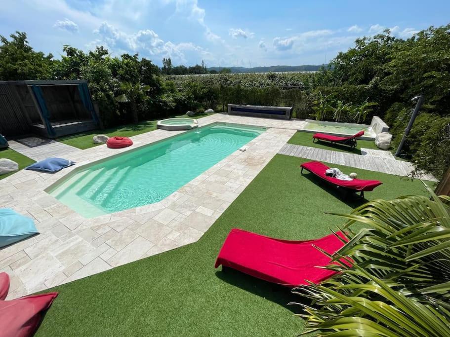 een zwembad met 2 ligstoelen en een zwembad bij Grande maison de charme avec piscine au coeur des vergers et vignobles in La Roche-de-Glun