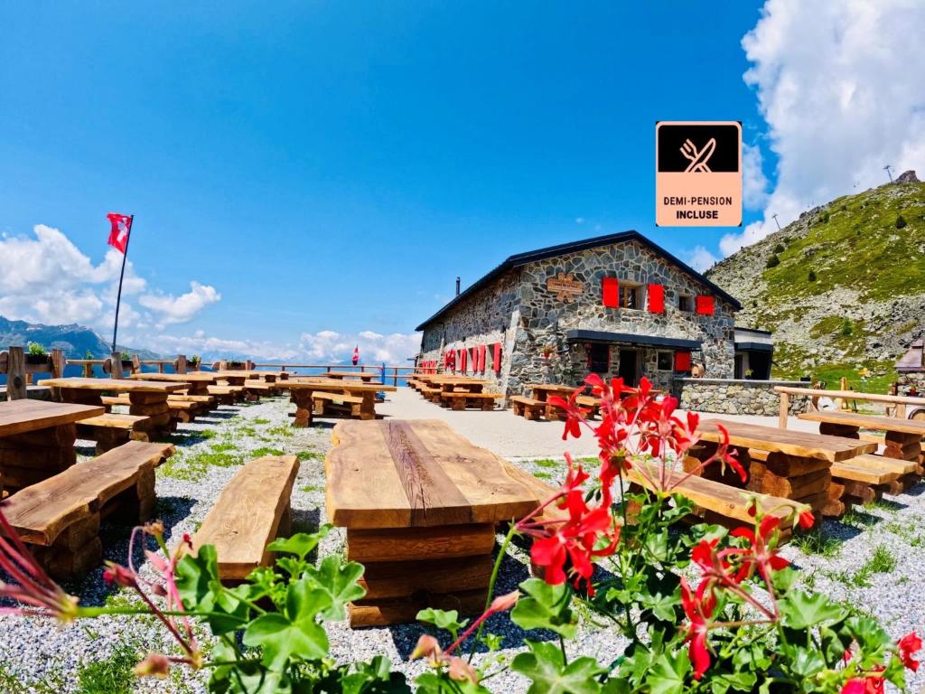 un groupe de bancs en bois devant un bâtiment dans l'établissement Cabane Bella-Tola, à Saint-Luc