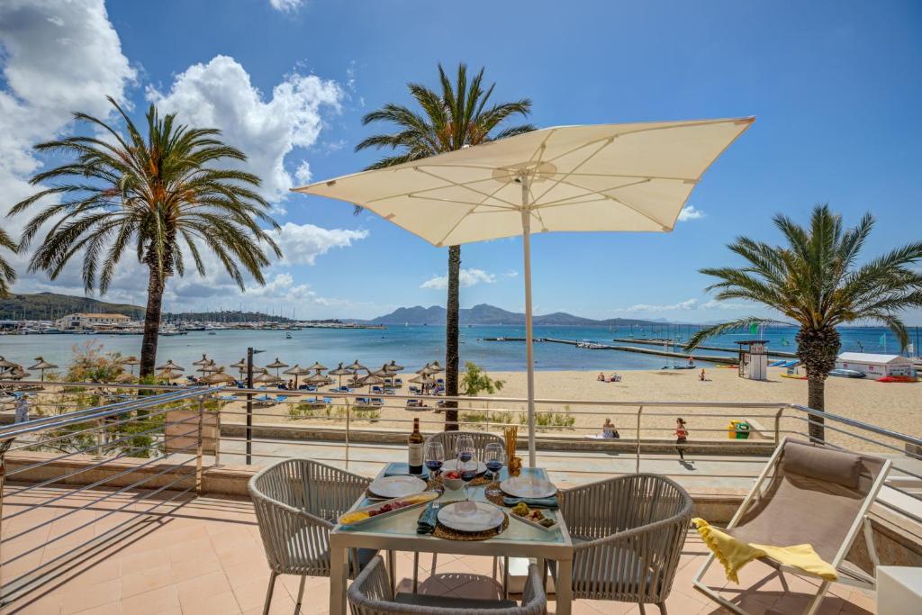 a table and chairs with an umbrella and a beach at Auborada 1A in Port de Pollensa