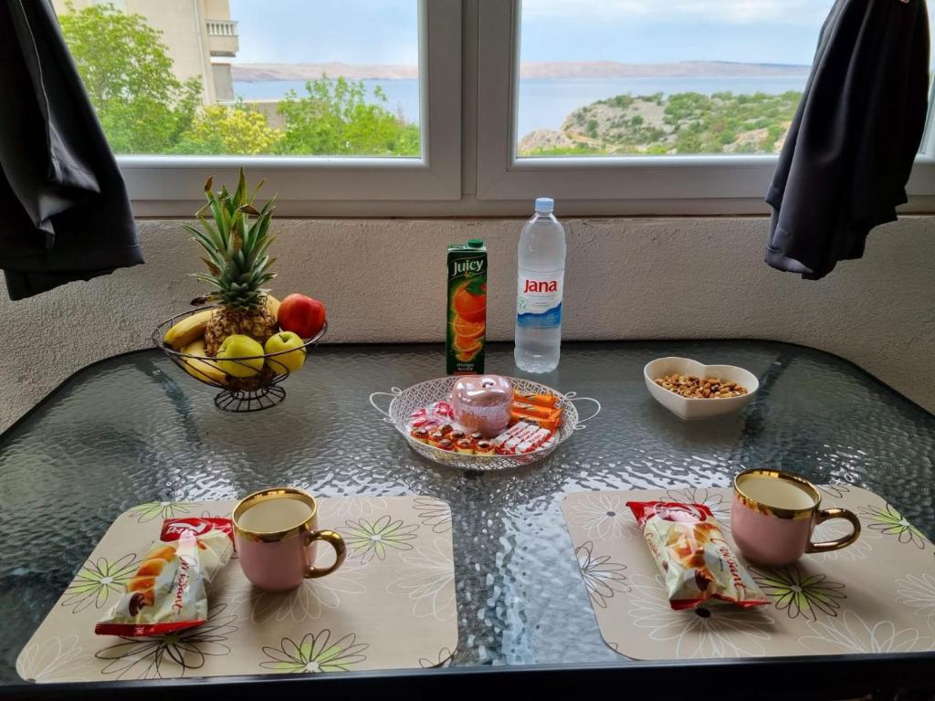 a table with two cups and a bowl of fruit at Apartmani 'Cvit' in Karlobag