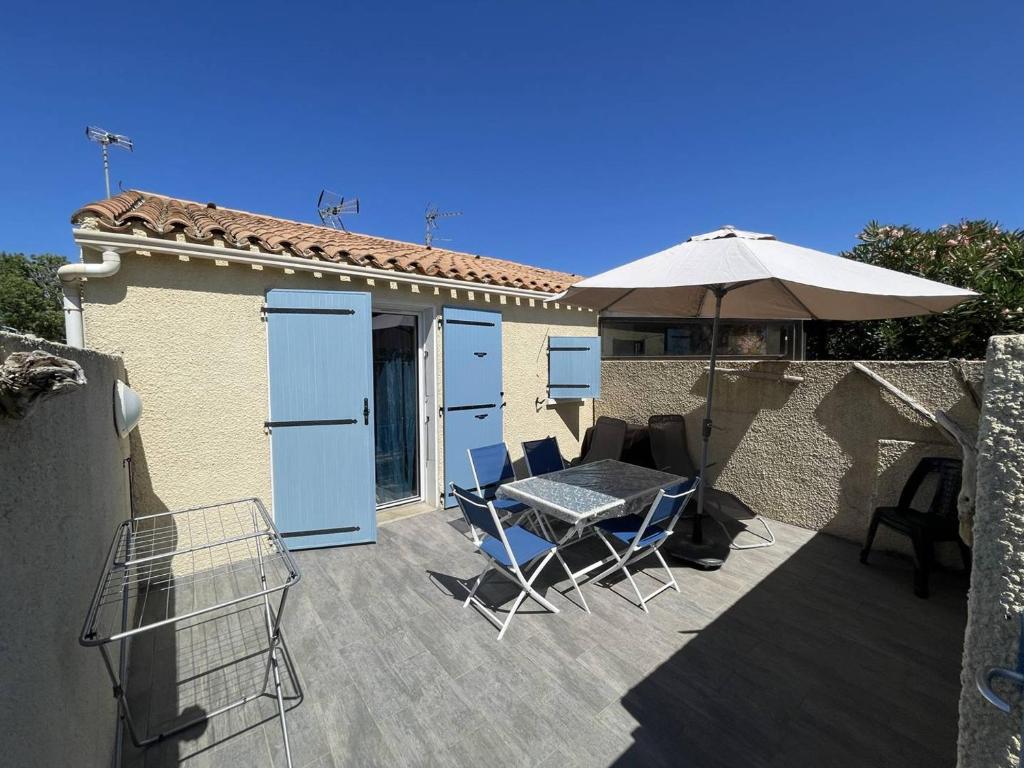 un patio avec une table, des chaises et un parasol dans l'établissement Charmante villa climatisée T2 mezzanine, 6 pers, terrasse ensoleillée, proche plage et commerces - FR-1-106-37, à Saint-Cyprien