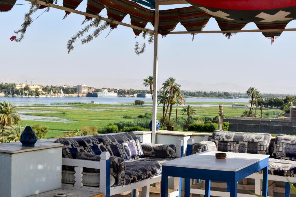 a patio with a table and chairs and a view of the water at Villa Rebecca in Luxor