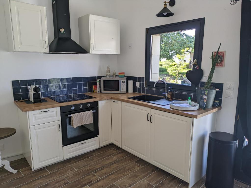 a kitchen with white cabinets and a sink and a window at Appartement Indépendant à Terrerort in Saumur