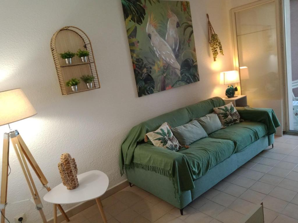 un salon avec un canapé vert et une table dans l'établissement Studio Rez de jardin St Aygulf, à Fréjus