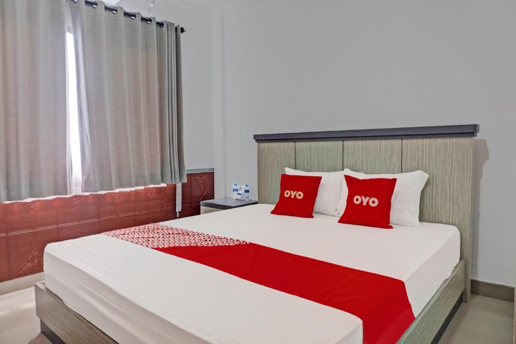 1 dormitorio con 1 cama grande con almohadas rojas en OYO 92518 De Luna Hotel, en Banjarbaru