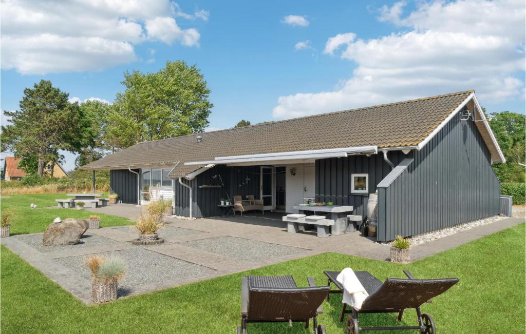 un bâtiment gris avec des chaises dans une cour dans l'établissement Gorgeous Home In Sams With Kitchen, à Onsbjerg
