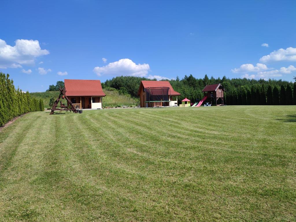 ein großes Grasfeld mit einem Haus und einem Spielplatz in der Unterkunft Domki Blizniaki in Żywki