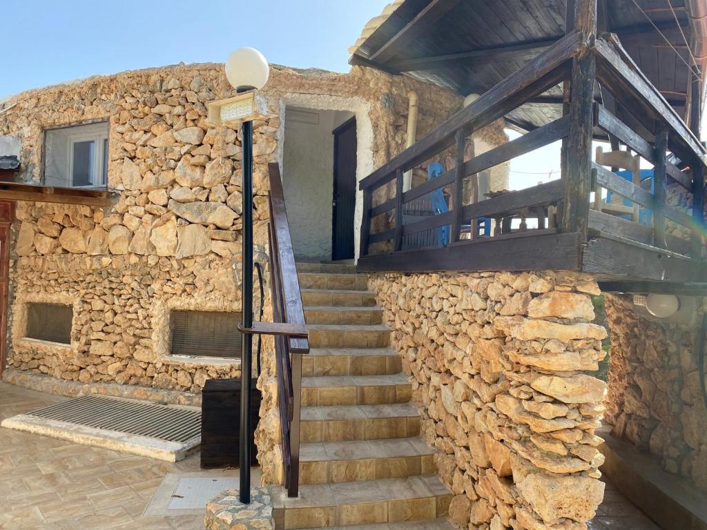 un bâtiment en pierre avec un escalier et un mur en pierre dans l'établissement Villaggio La Roccia camping, à Lampedusa