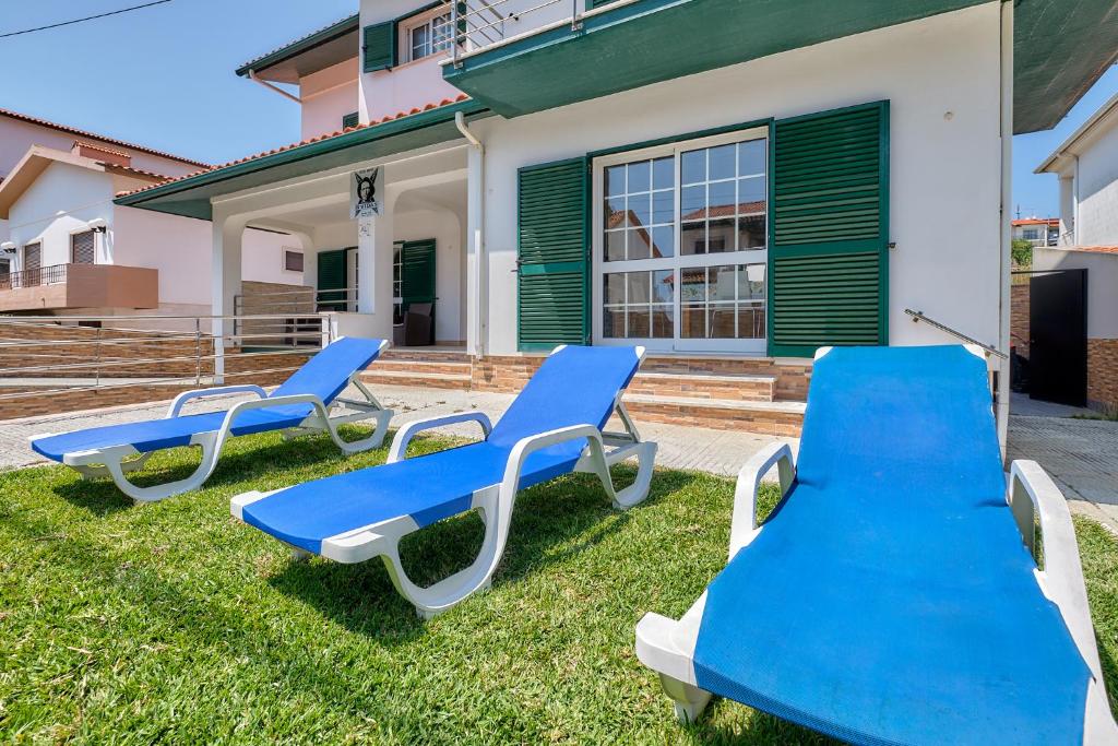 three blue chairs in the grass in front of a house at NVidas in Figueira da Foz