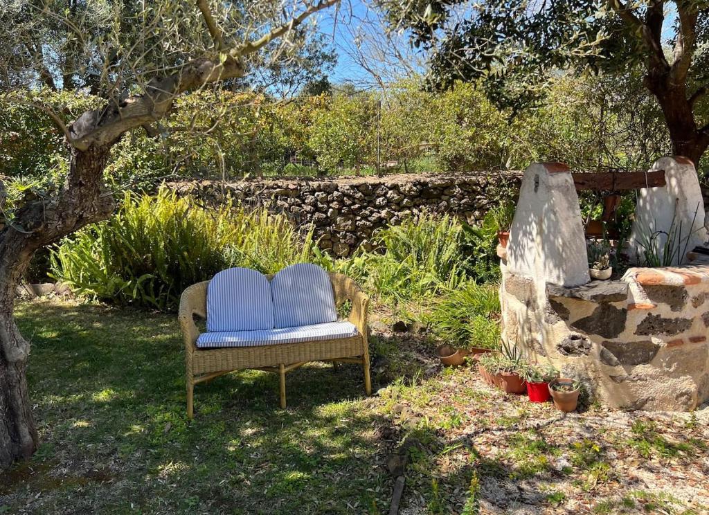 a chair sitting in a yard next to a stone wall at Putzurile House in Orosei