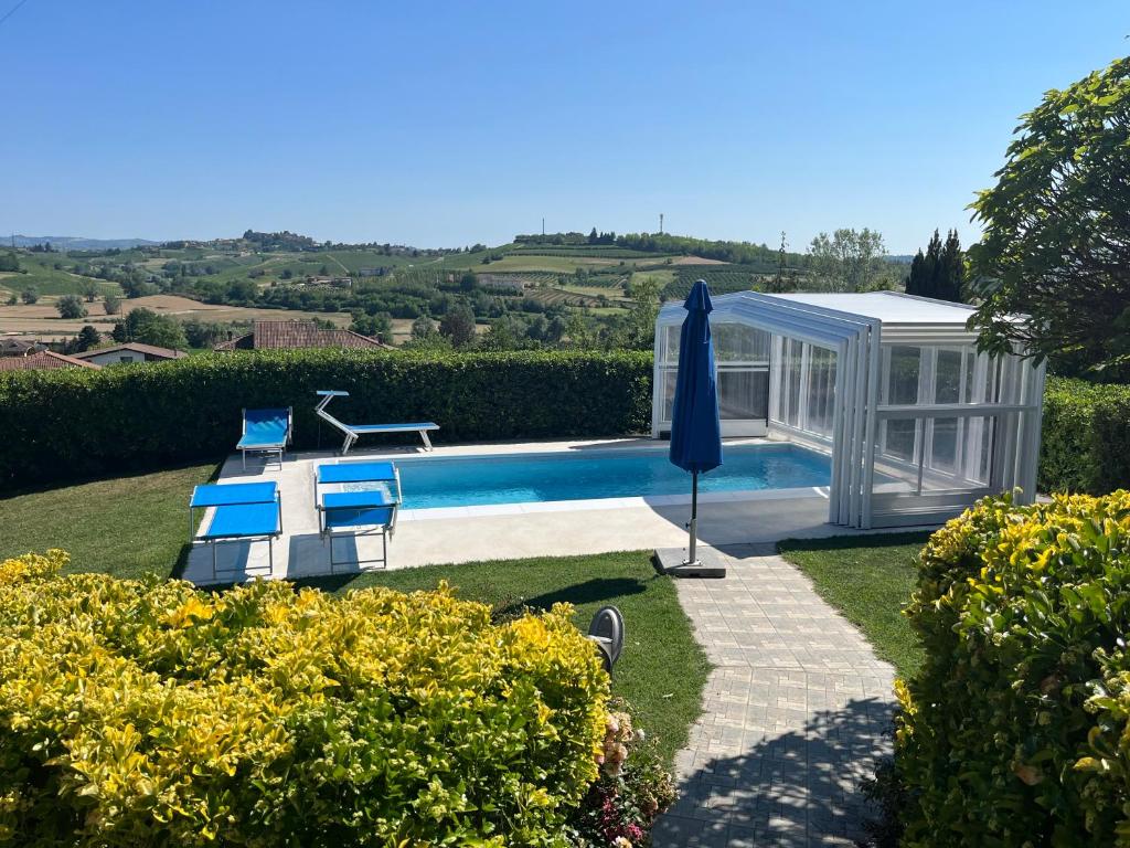 a garden with a swimming pool and a house at La Casa Blu in Montegrosso dʼAsti