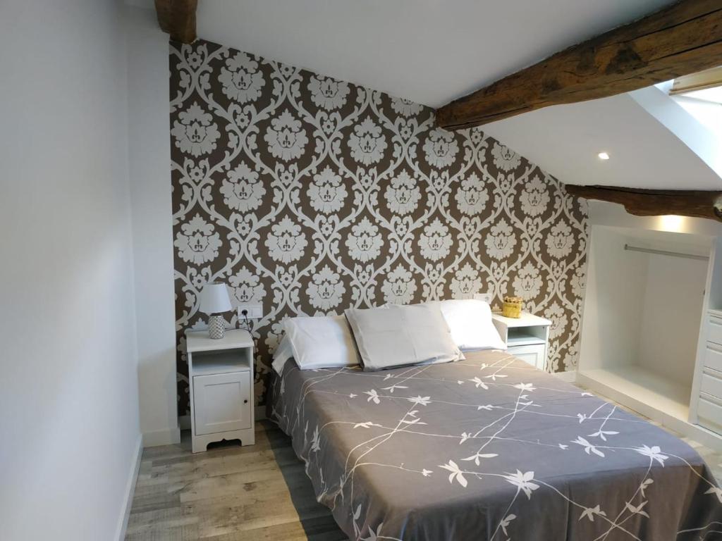 a bedroom with a bed and a wall with wallpaper at RUA NOVA APARTMENT ATICO 3º,a 200m CATEDRAL,PS 4 y NETFLIX in Santiago de Compostela