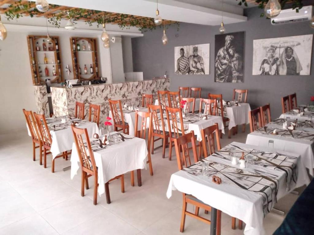 a dining room with white tables and wooden chairs at Aquaview Amina's rental apartment in Bijilo