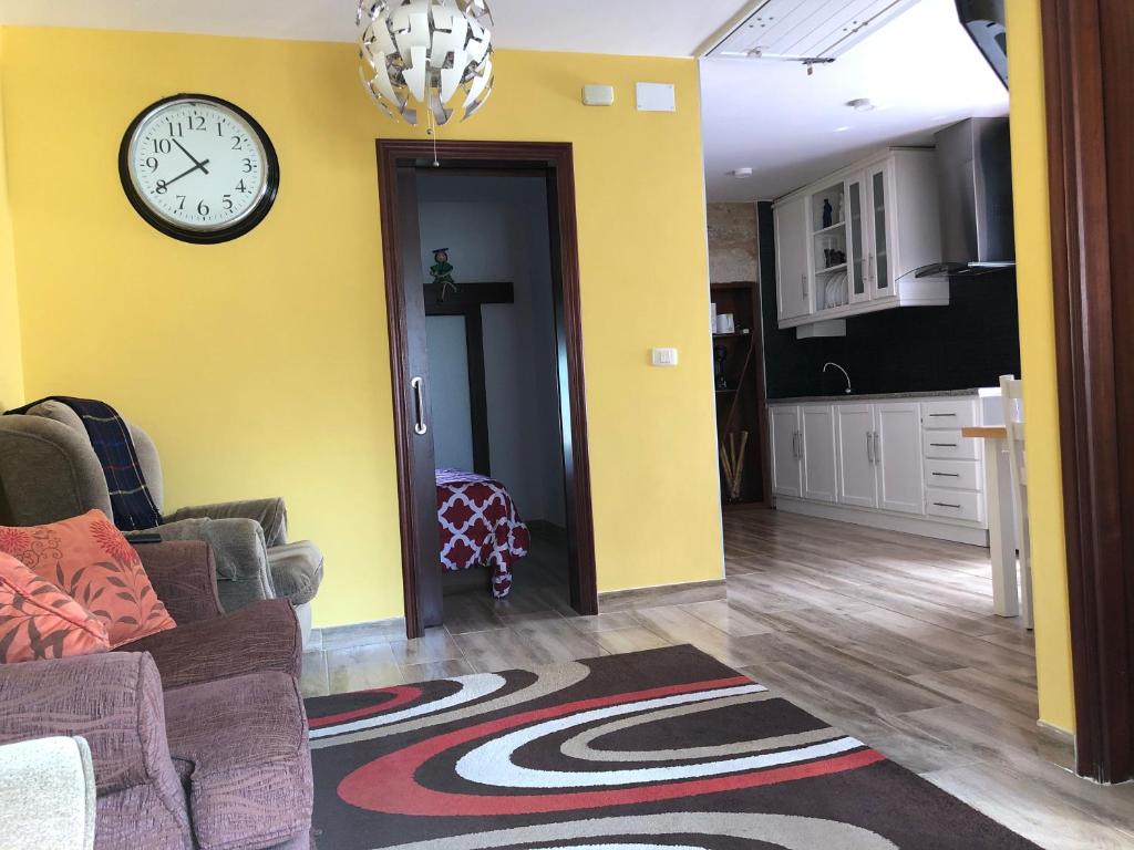 ein Wohnzimmer mit einer Uhr an einer gelben Wand in der Unterkunft Precioso apartamento Fina la Caprichosa en centro de Mondariz in Mondariz