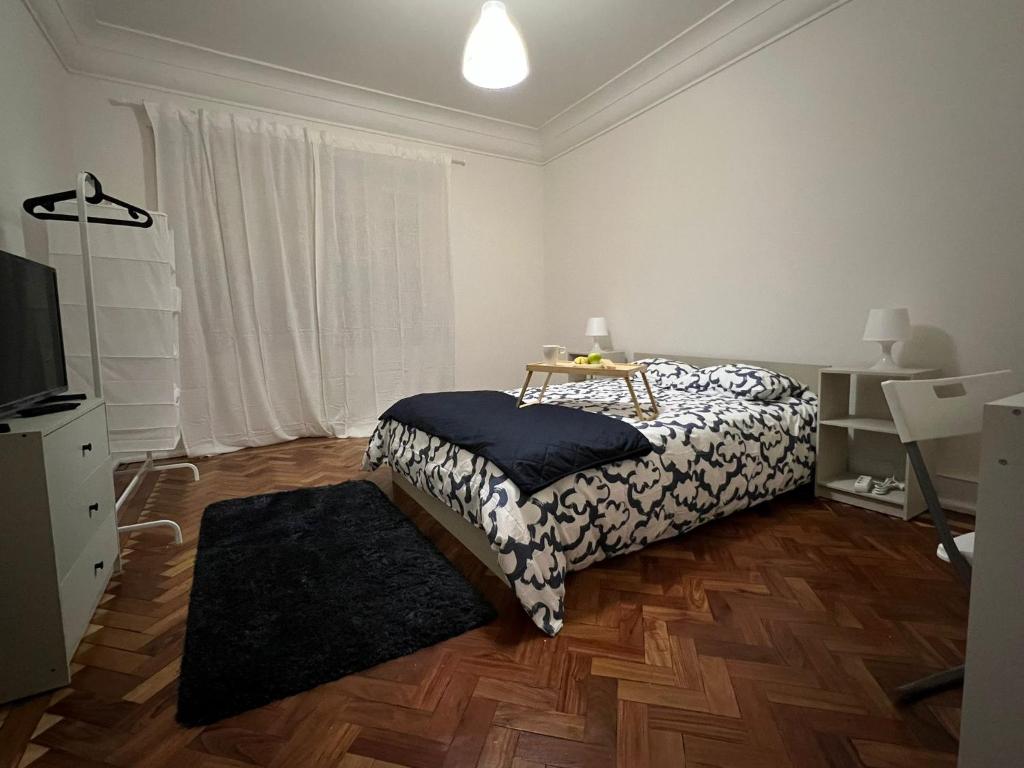 a white bedroom with a bed and a television at SÓLO HABITACIÓN GRANDE CON BALCOn in Lisbon
