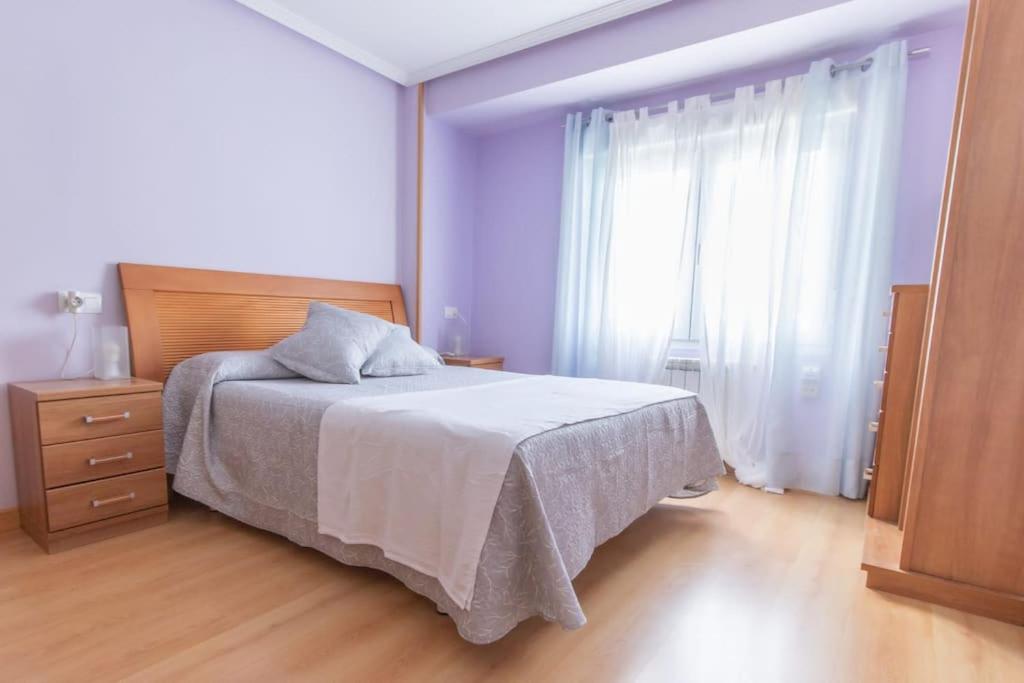 a bedroom with a bed and a large window at Apartamento Subráu in Gijón