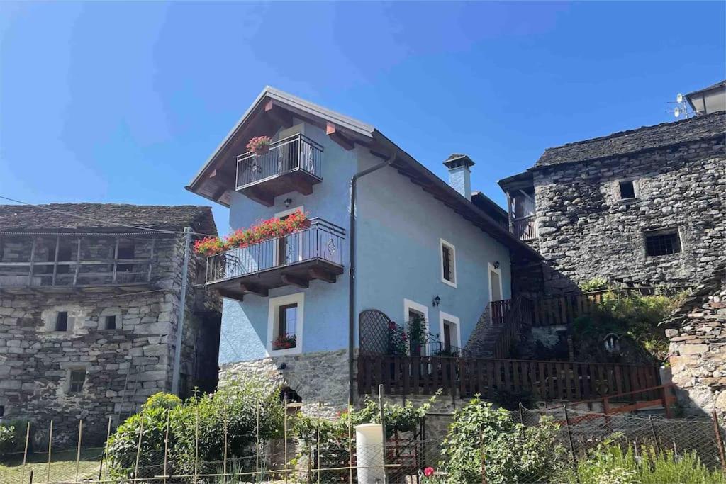 un edificio bianco con balcone e recinzione di CASA DEL CIOS calda e intima casetta immersa nel verde delle montagne a Alpe Basciumo