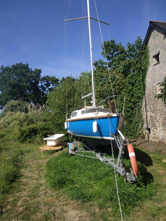 un barco azul sentado en el césped junto a una casa en Edel de la Touche Balard, en Val Couesnon