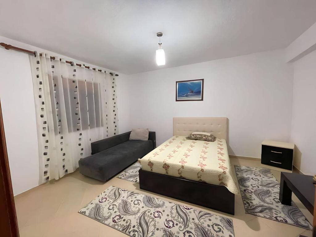 een slaapkamer met een bed en een bank erin bij Guri Guest House in Pogradec