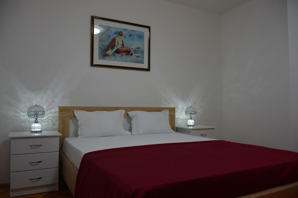 a bedroom with a bed with a red bedspread and two lamps at B&B Ana in Virpazar