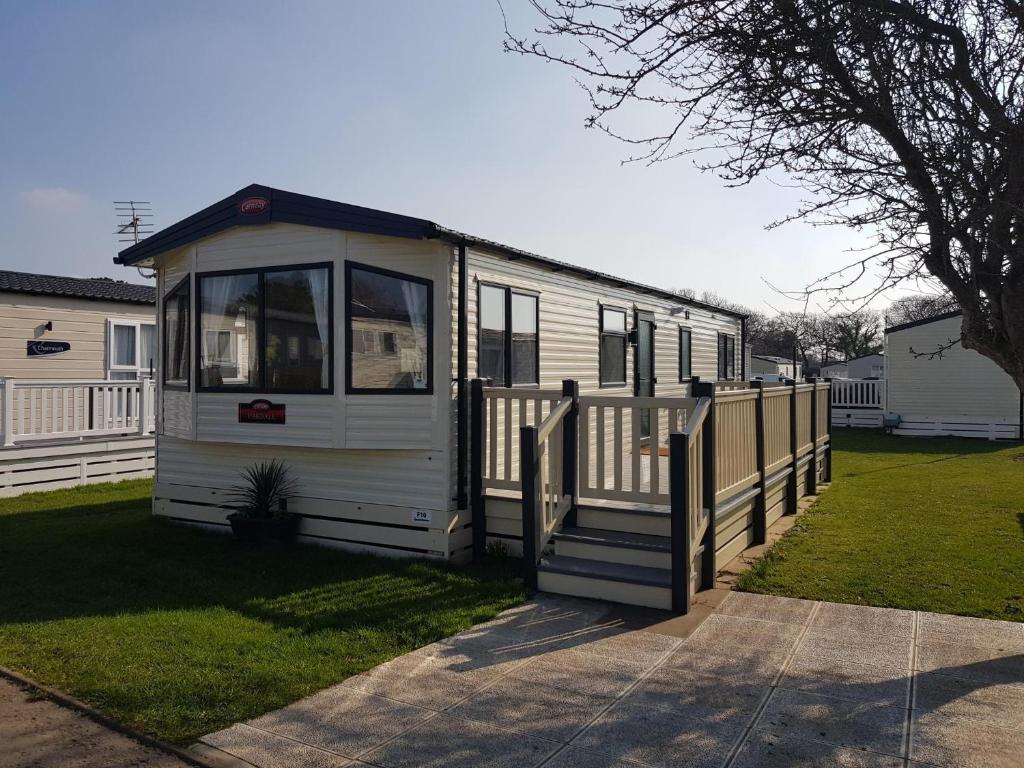 a small white trailer with a wooden fence at 2 Bedroom Lodge, Milford on Sea in Milford on Sea