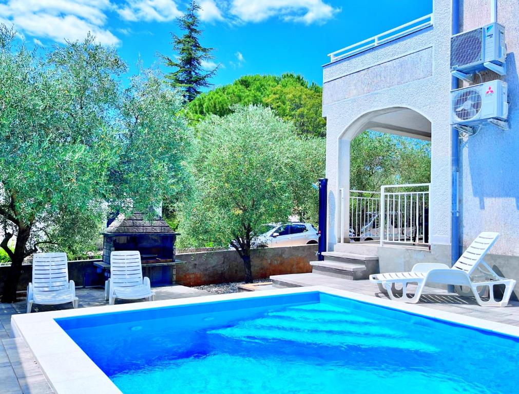 a swimming pool with two chairs and a fireplace at Adria Holiday Home in Pinezici