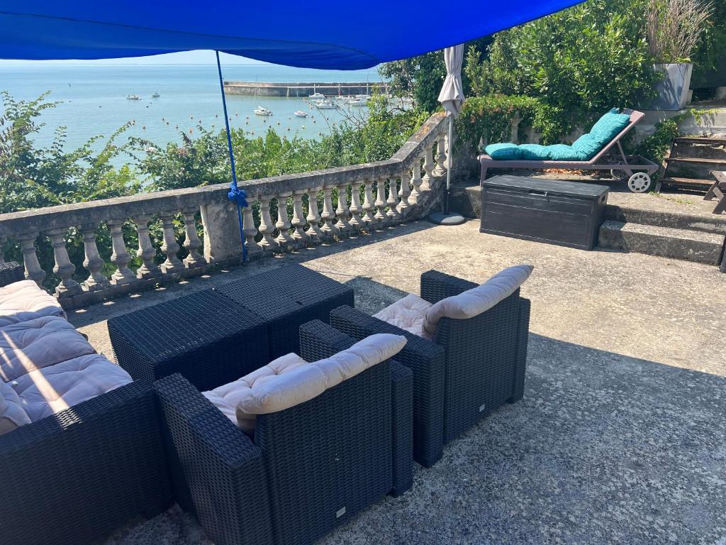 un patio con mesa, sillas y sombrilla en Villa TOUSVENTS en Saint-Georges-de-Didonne