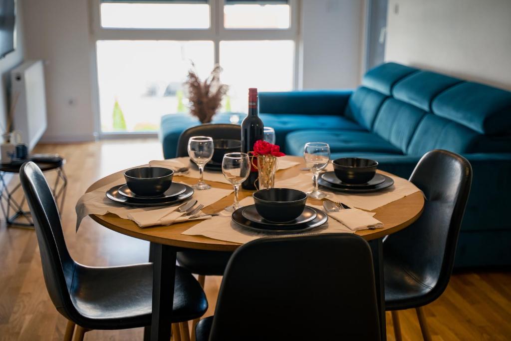 een houten tafel met wijnglazen en een blauwe bank bij LAGATOR LUX in Loznica