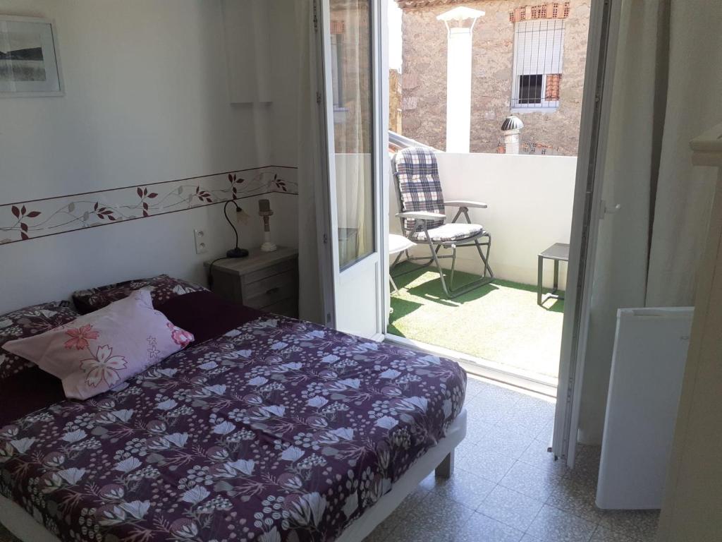 a bedroom with a bed and a balcony with a chair at Serge le belge sejour chez l habitant in Lézignan-Corbières