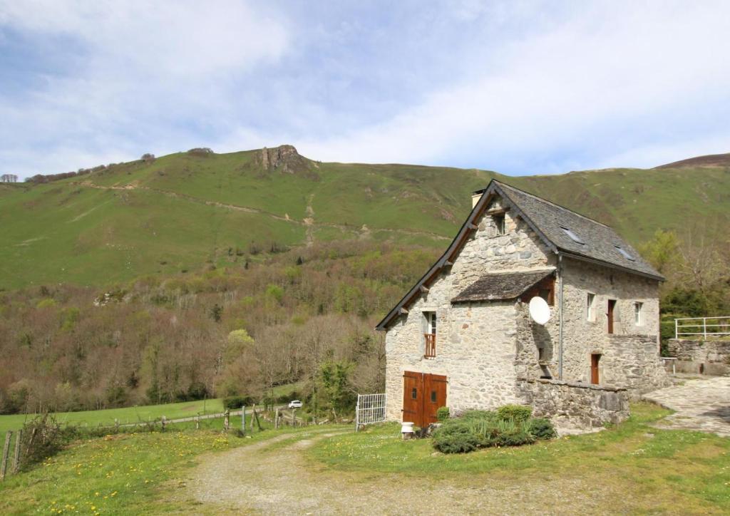 un ancien bâtiment en pierre avec une montagne en arrière-plan dans l'établissement Petit aoulet, à Accous