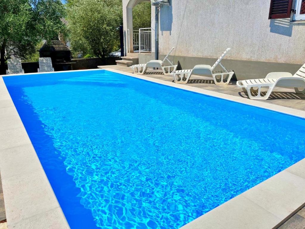 a swimming pool with blue water in a yard at Adria Holiday Home in Pinezici