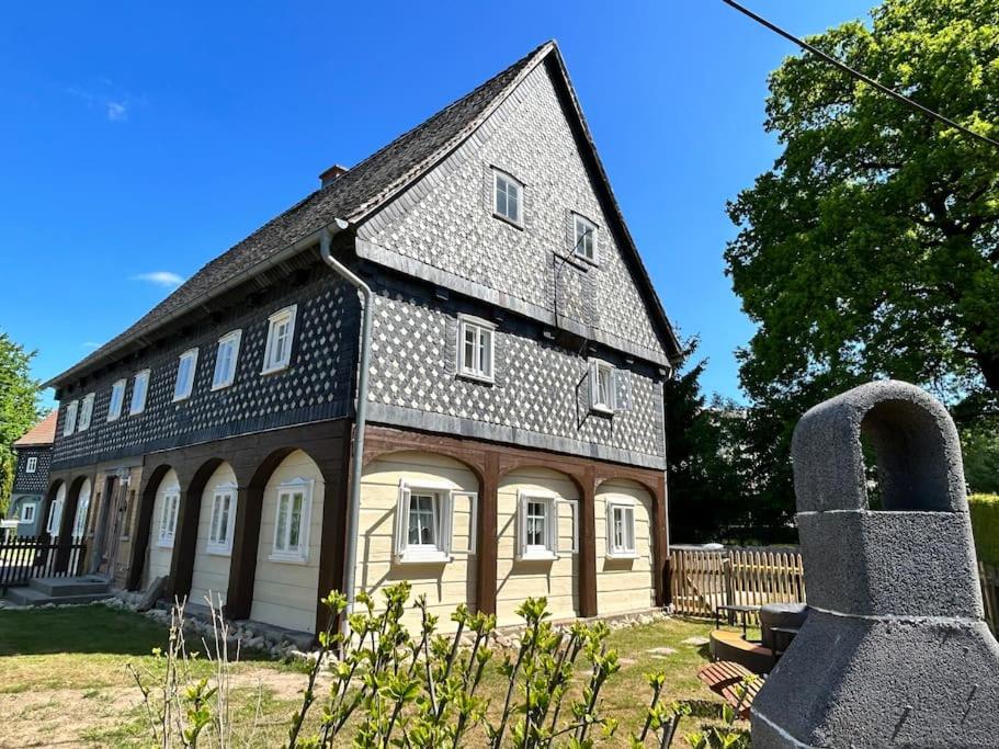 une ancienne maison avec un toit gris et une tombe dans l'établissement Ferienhaus Hexe mit Whirlpool, Sauna, Garten, à Großschönau