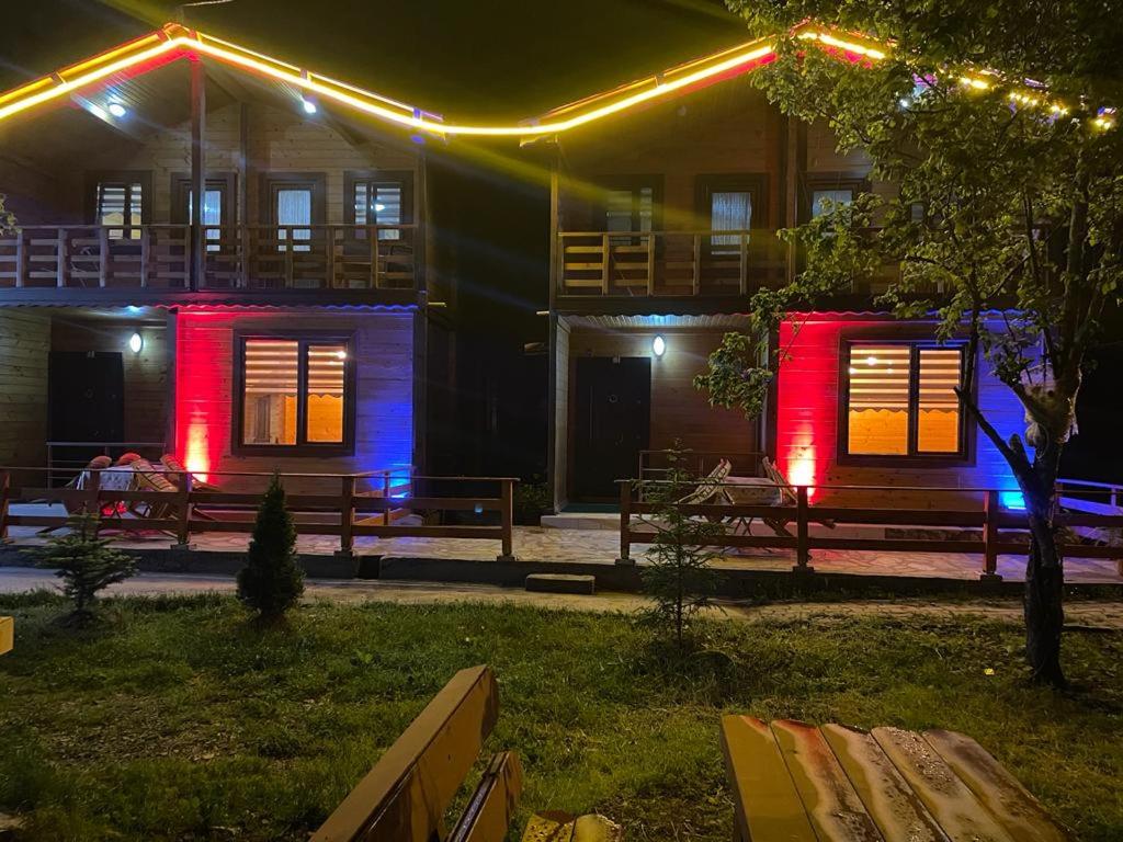 ウズンギョルにあるMimeh Apartmentの赤と青の灯りを前に建つ家