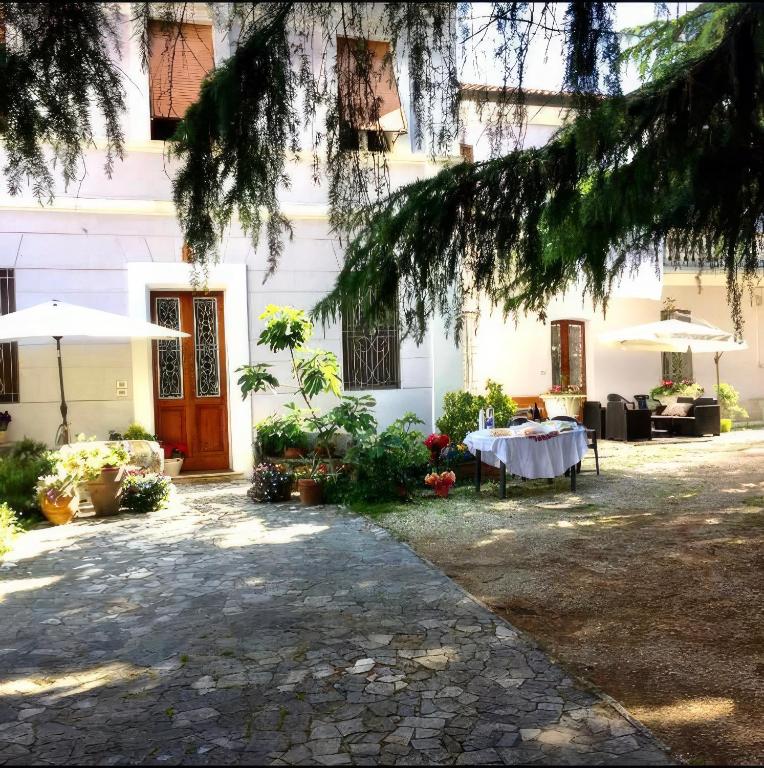 a table in front of a white building with an umbrella at Villa Viola in Forlì