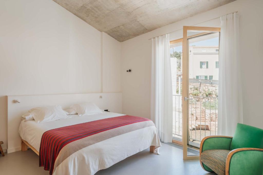 a white bedroom with a bed and a window at Ses Sucreres Small & Slow Hotel in Ferreries