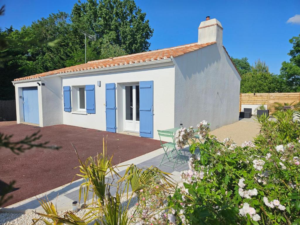 un pequeño edificio blanco con puertas azules en Charmante Maison à 500m de la plage, en La Tranche-sur-Mer