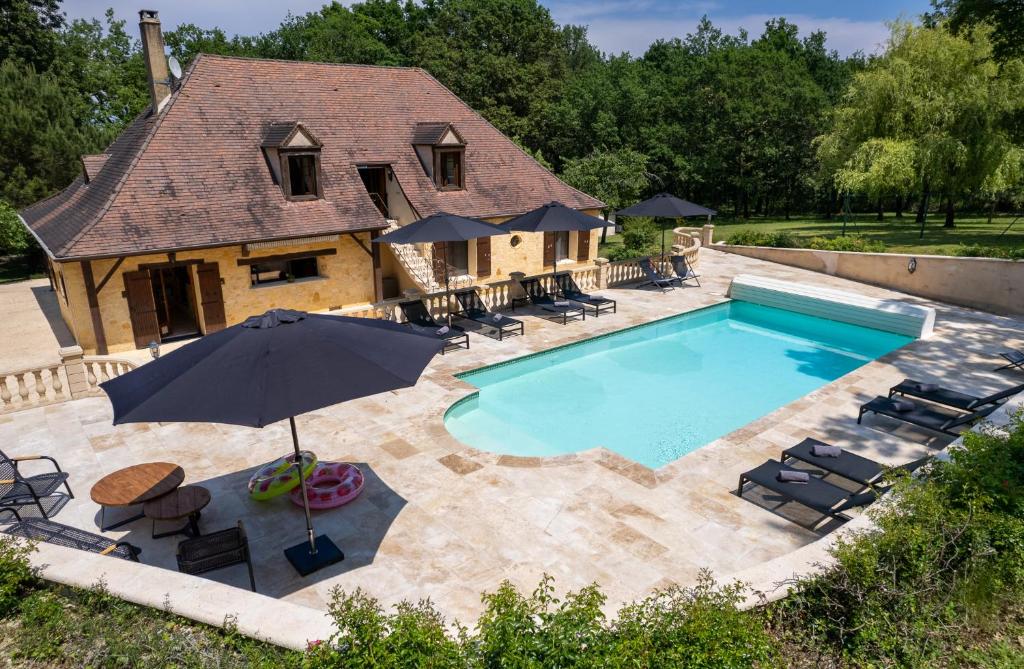 une vue aérienne d'une piscine avec des chaises et un parasol dans l'établissement Maison Saint-Blaise Rampieux, à Rampieux