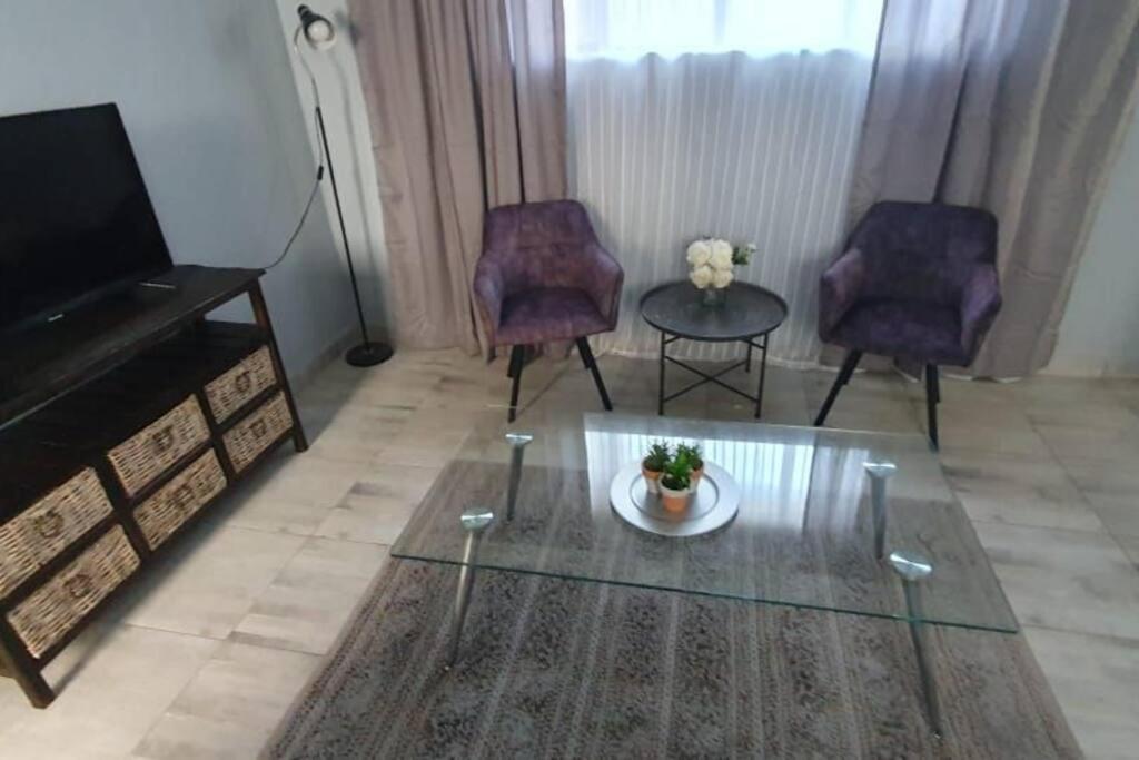 sala de estar con 2 sillas, mesa y TV en Cozy Little Nest, en Pretoria