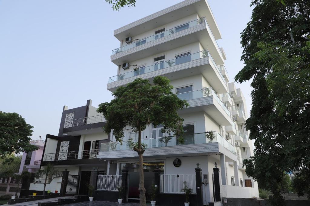 un bâtiment blanc avec un arbre devant lui dans l'établissement Opulent Inn by Lime Tree Hotels, à Greater Noida